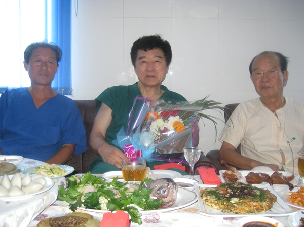 ▲ 2012년, 명예의학박사증 받은 소식을 듣고 이젠 은퇴한 나의 영원한 동행 리화일 동무가 평양의학대학병원에 찾아와 축하 꽃다발을 내게 안겨주고 떠났다. 왼쪽부터 박송철, 오인동, 장창호.